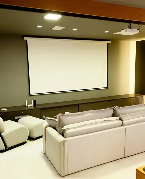 Sala de cinema com telão, sofá largo e mesa de sinuca