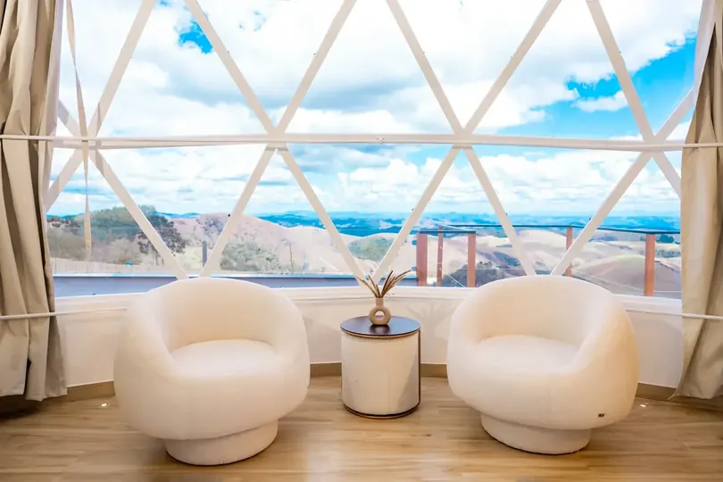 Poltronas diante da janela triangular do domo, com vista para a serra